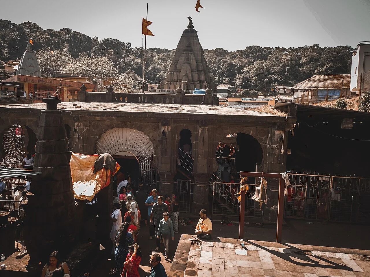 The dark stone entrance and spire of Bhimashankar Temple, with devotees in the courtyard